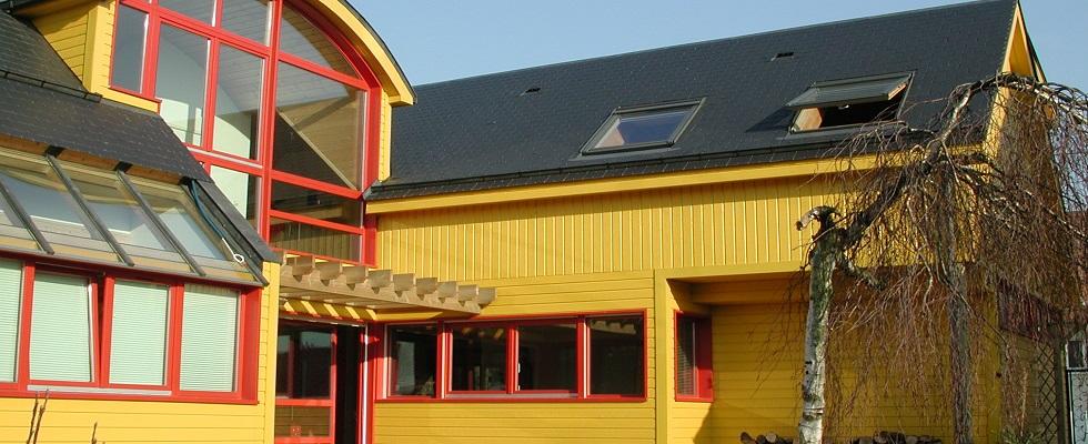 Maison en ossature bois, bardage peint, verrière, pergola, toit en voûte.