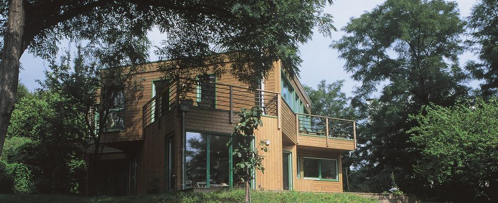 Maison en ossature bois sur deux niveaux, terrasses, baies vitrées, toit plat.