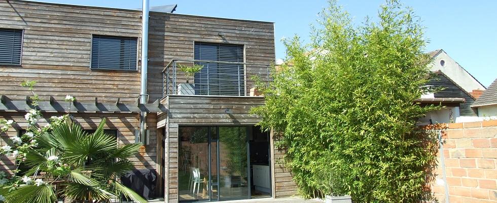 Maison en ossature bois sur deux niveaux et bardage en bois naturel, pergola, balcon, baies vitrées.