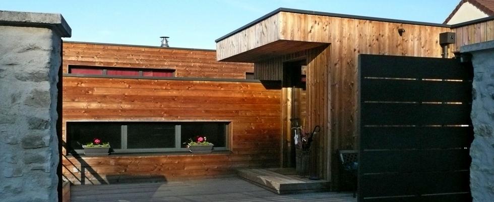 Maison en ossature bois et bardage en bois naturel, toit plat, garage, plusieurs niveaux en décalé.
