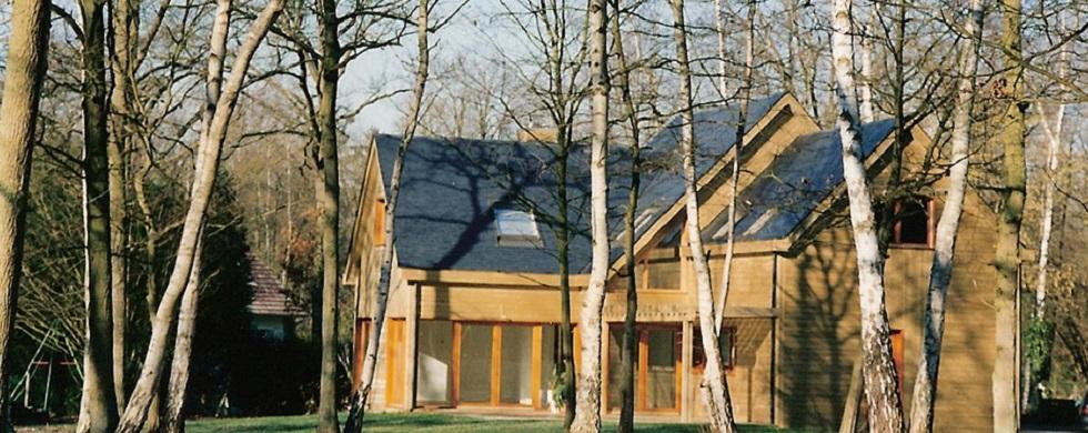 Maison en ossature bois, bardage en bois naturel, toit double pente, baies vitrées.